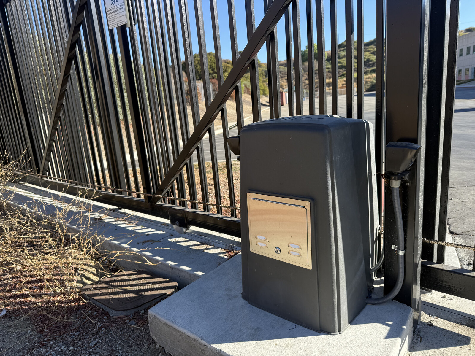 Slide gate operator installed on a concrete pad beside an ornamental steel fence
