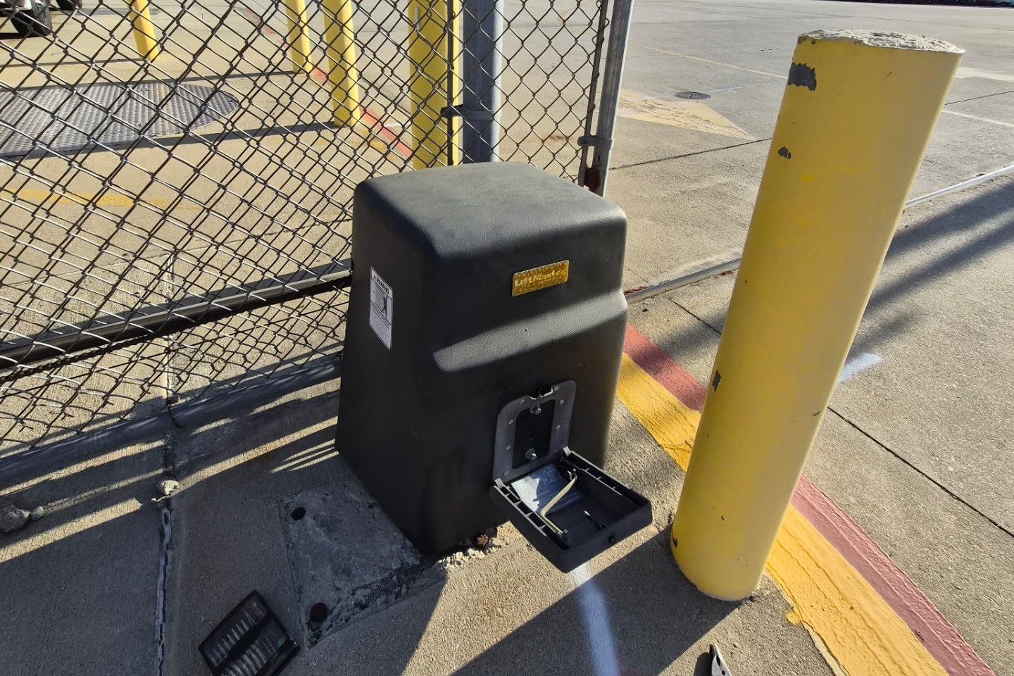 LiftMaster slide gate operator installed on a concrete pad behind a chain-link fence line