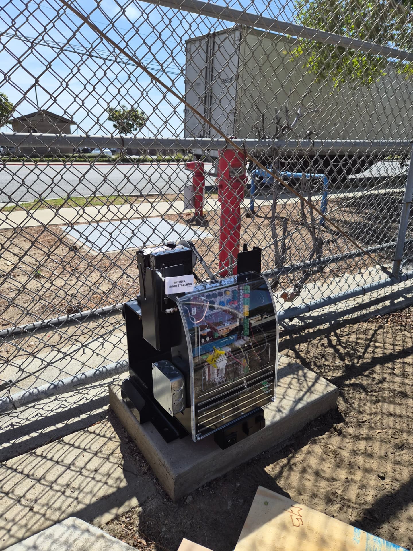 Slide gate operator and control box installed beside a chain-link fence