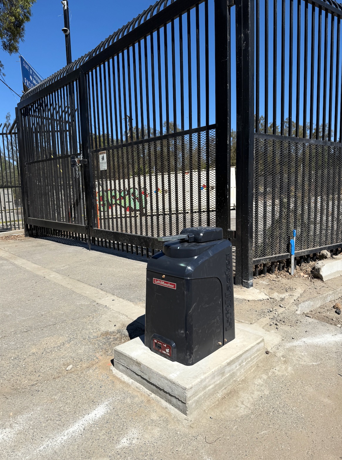 LiftMaster slide gate operator installed on a concrete pad beside an ornamental steel gate