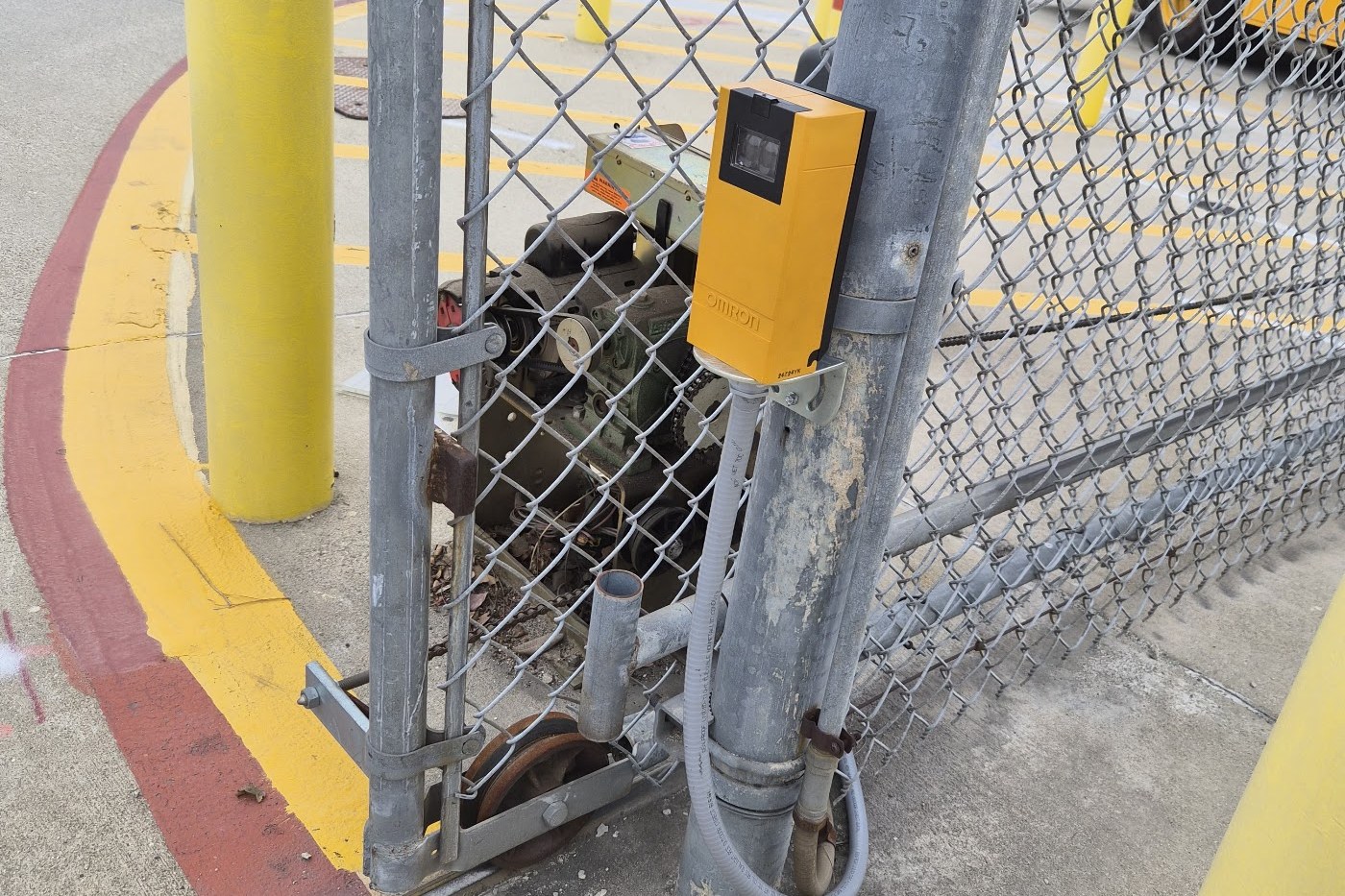 Galvanized chain link gate with a photo safety eye sensor at a school campus entrance