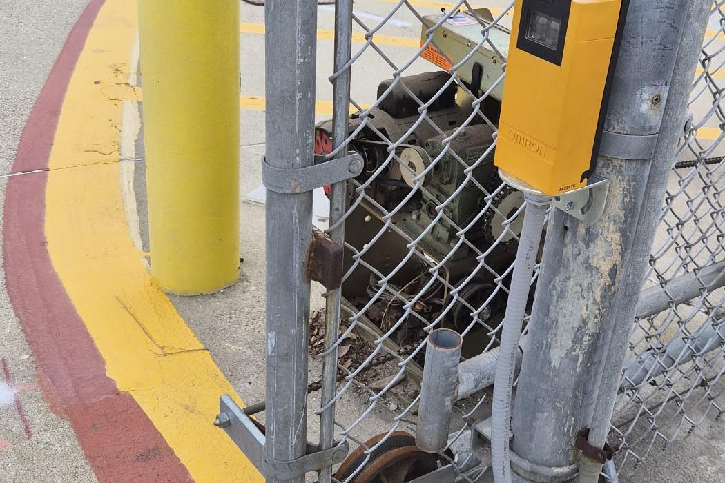 Chain link vehicle gate fitted with a safety sensor at a school bus yard