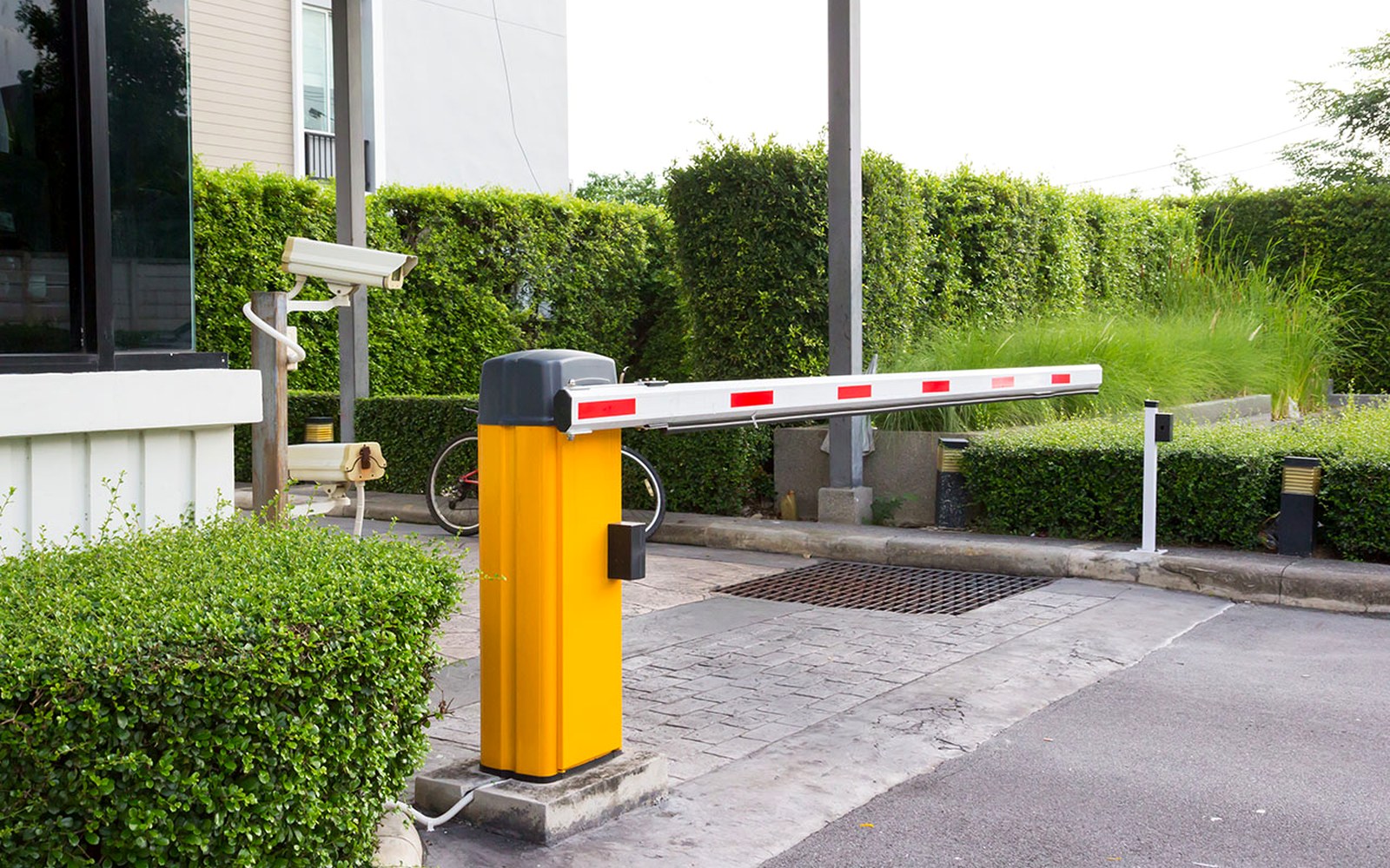 Red and white barrier arm across the vehicle entrance lane of a concrete parking structure