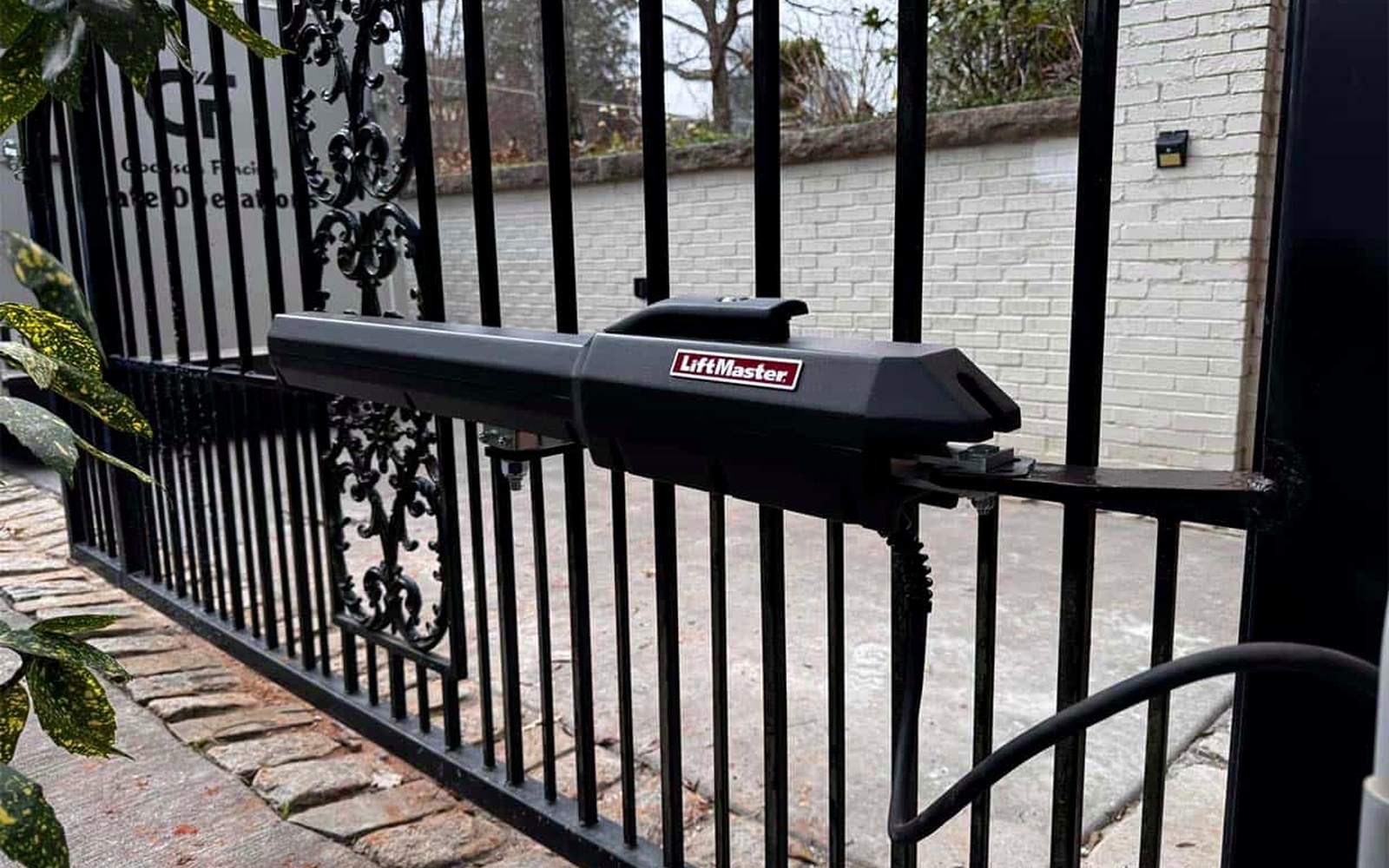 Swing gate operator arm mounted on an ornamental iron driveway gate